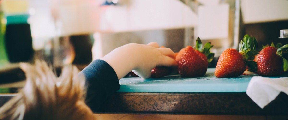 Boy grabbing strawberries on a counter